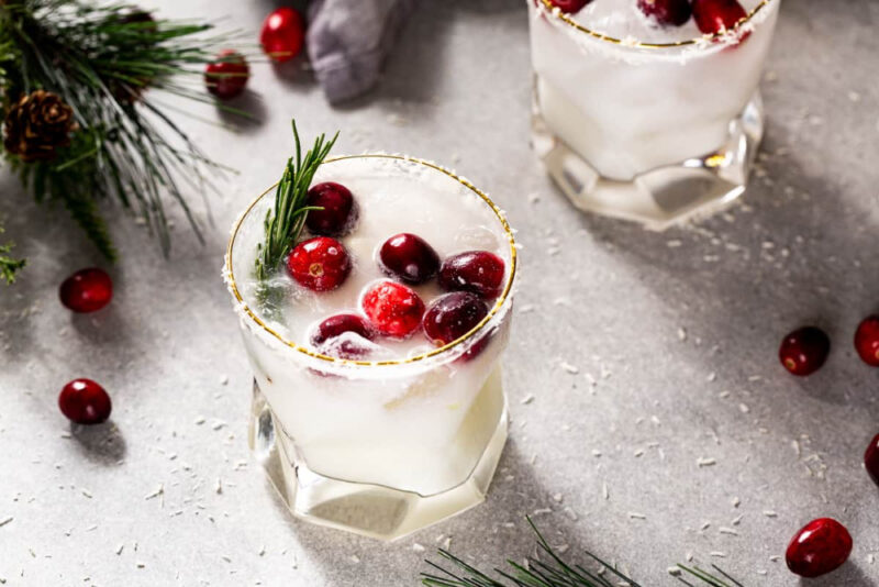 white margarita garnished with cranberrries and rosemary in a highball glass