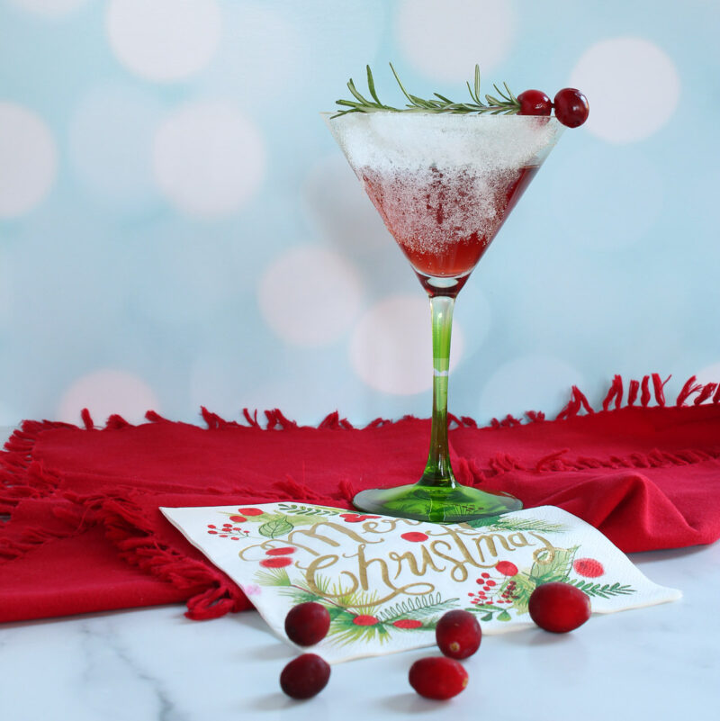 Pom Pom Christmas cocktail with cranberries and rosemary garnish on red napkin