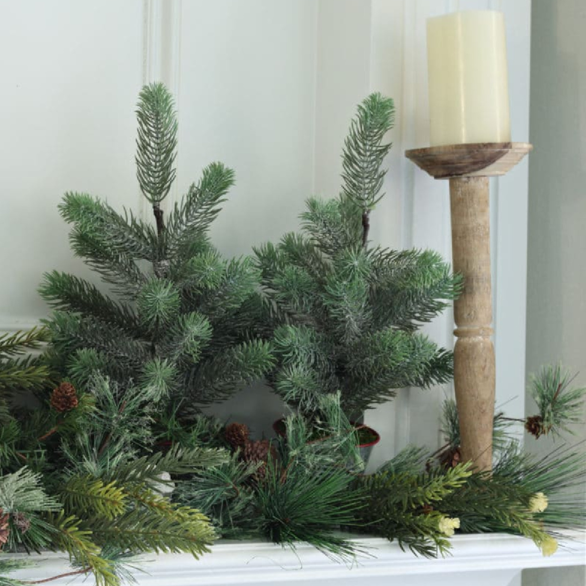 winter mantel decor with greenery and wood candlestick and cream candle