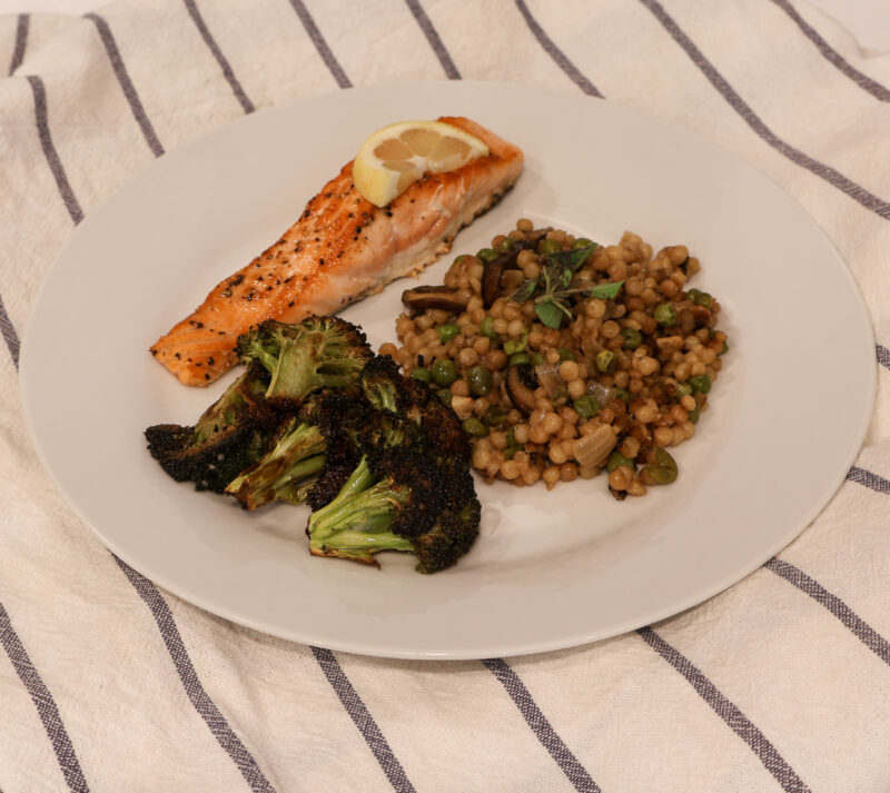 toasted couscous with salmon and roasted broccoli on white plate