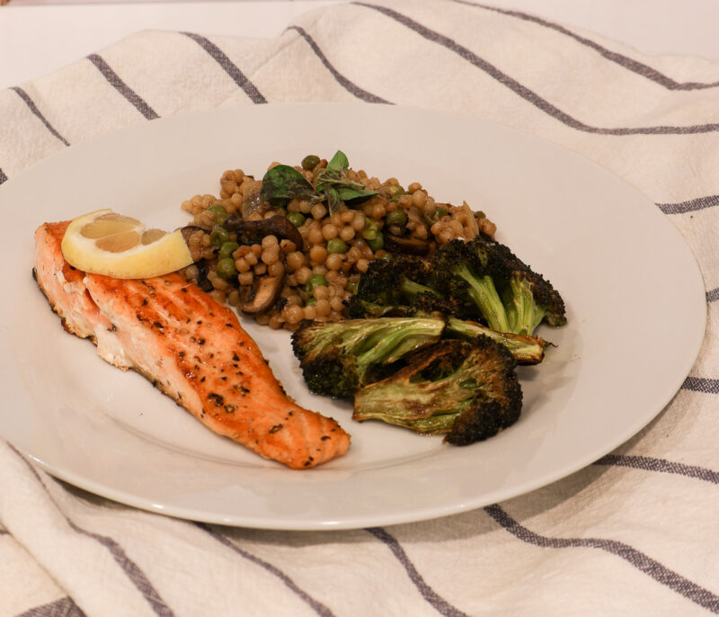 toasted couscous with salmon and roasted broccoli on white plate