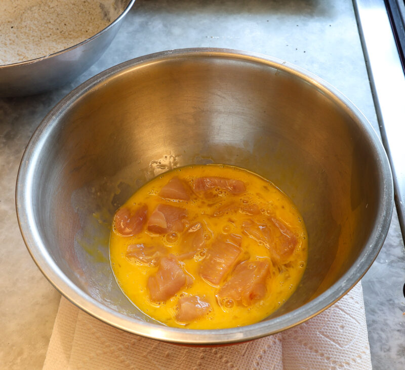 chicken cubes in bowl of beaten eggs