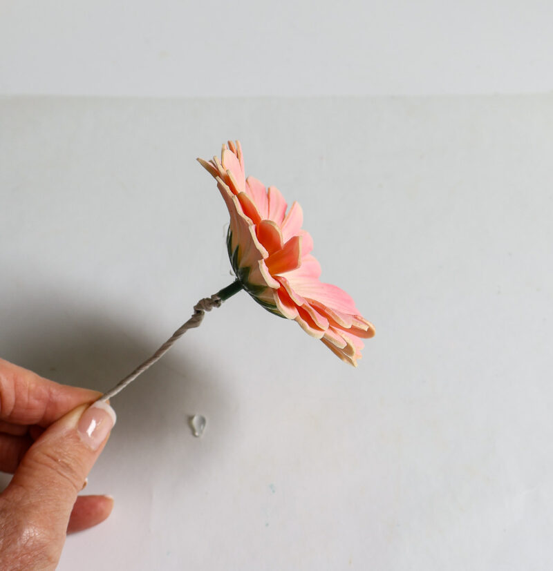 holding pink faux flower by florist wire