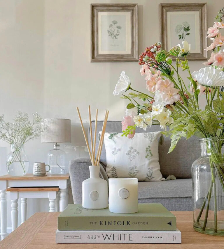 light summer decor with greenery in clear glass vases on coffee table with sofa and art
