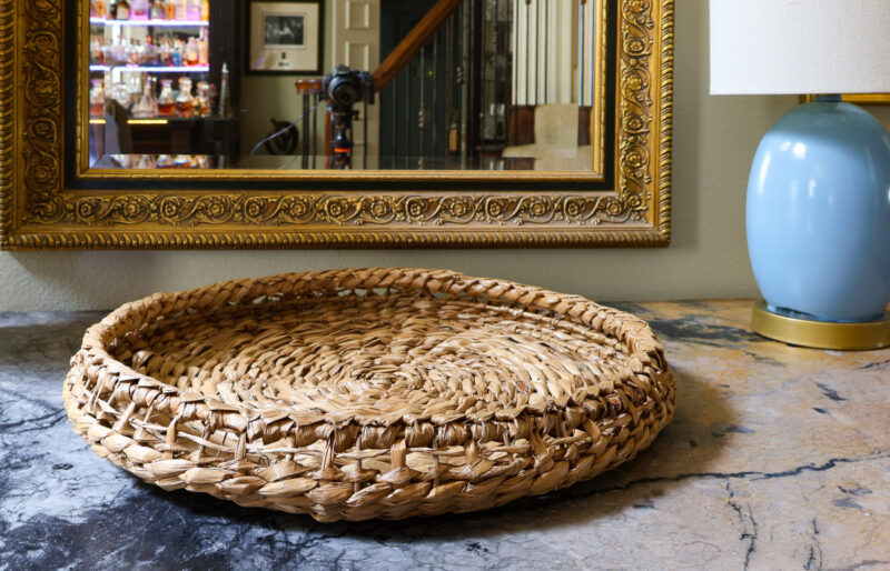 round woven tray on marble top dresser