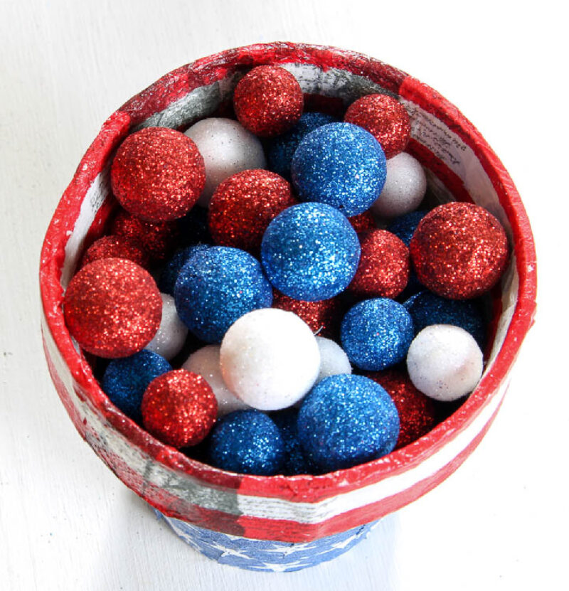red white and blue decoupaged terra cotta pot decorated for 4th of July with glitter balls in red, white, and blue