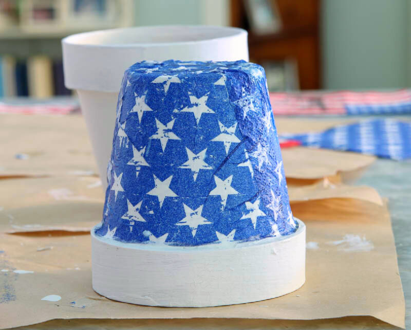 terra cotta pot decoupaged with blue napkin and white stars upside down
