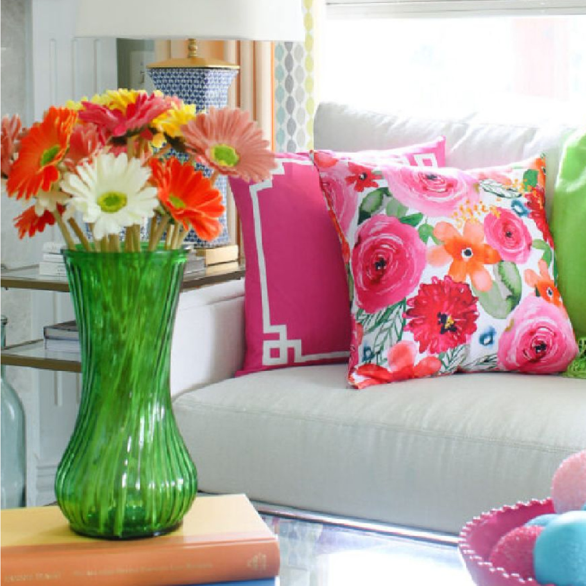 bright floral pillows, pink pillows, and bright flowers in green vase