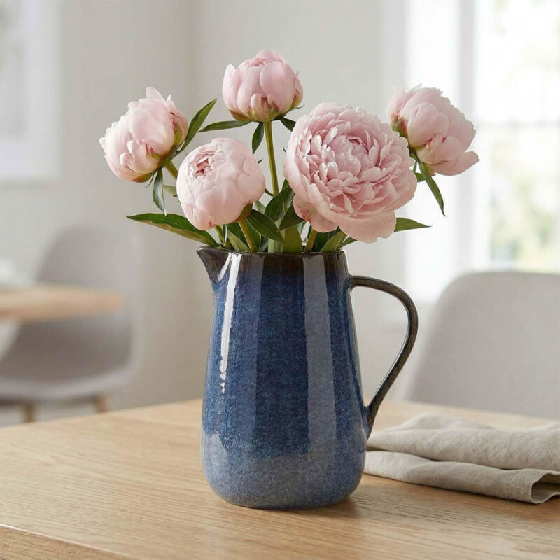 blue pitcher full of pink flowers