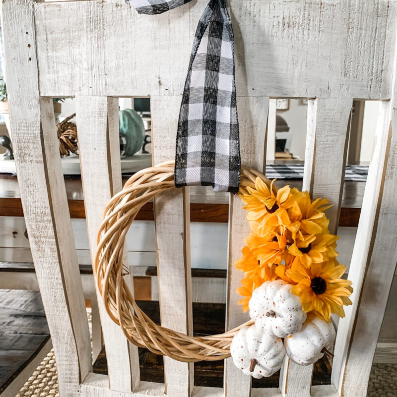 small fall DIy wreath with pumpkins and flowers on back of chair