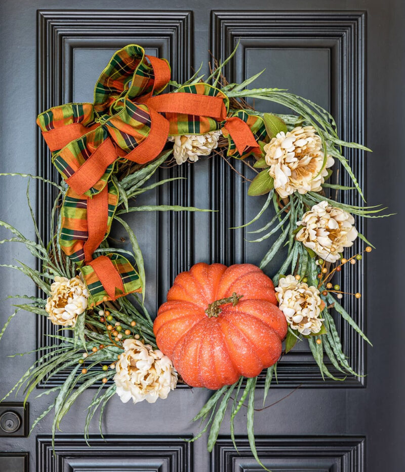 pumpkin and greenery fall wreath on black front door