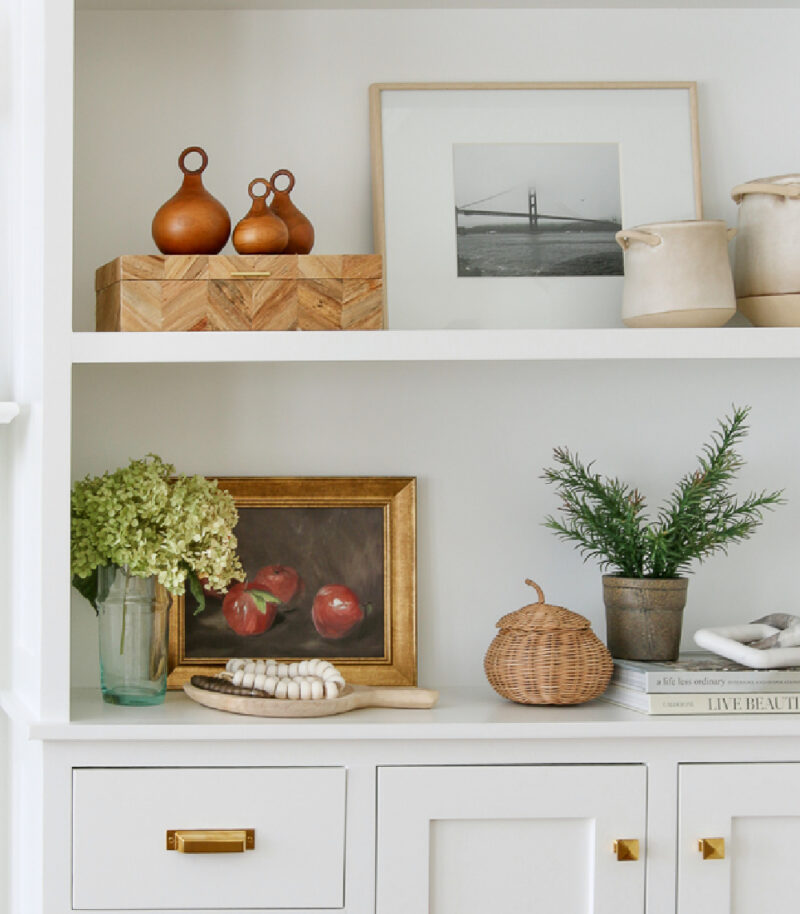 fall decor with woven pumpkin, woven basket, hydrangeas, and neutral colors on bookcase