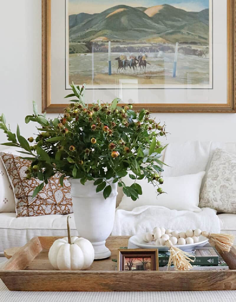 white vase with green florals on tray with white pumpkin