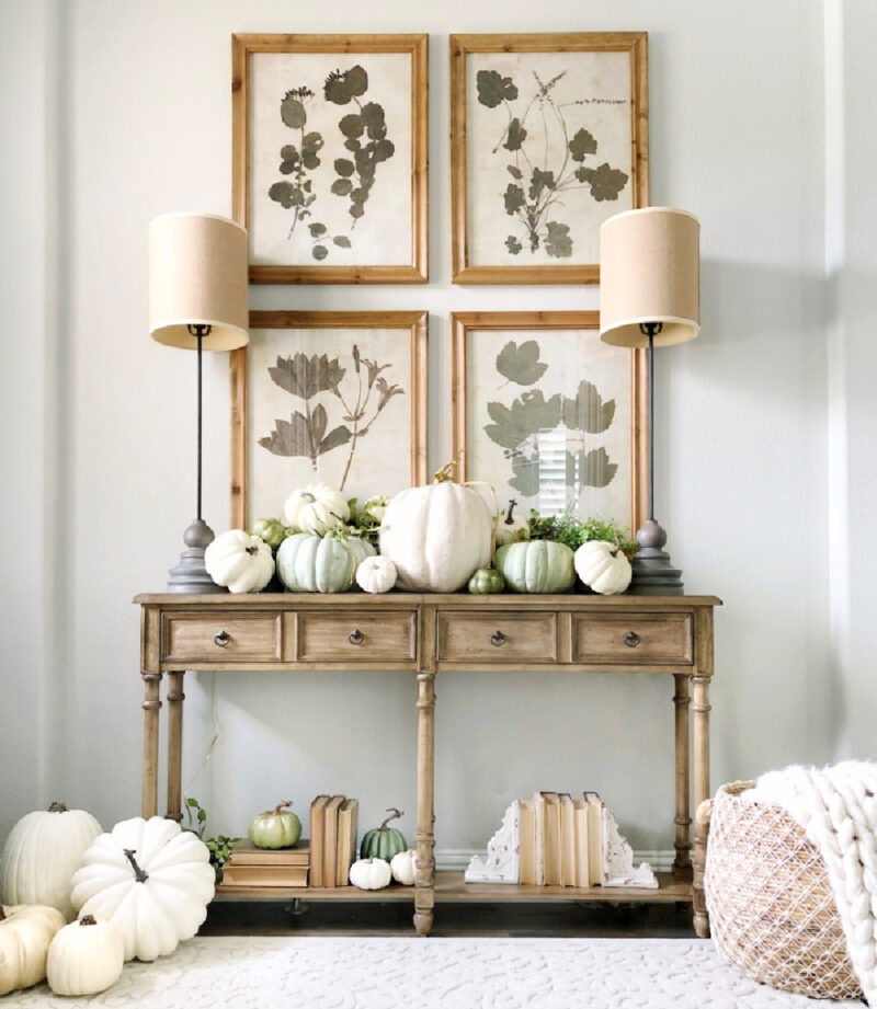 entry table decorated for fall with art and white pumpkins