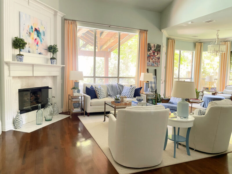 living room with large picture winder, white furniture and fireplace and mantel