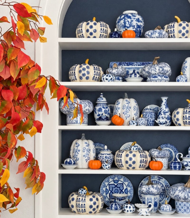 blue and white chinoiserie fall bookshelf with pops of orange pumpkins