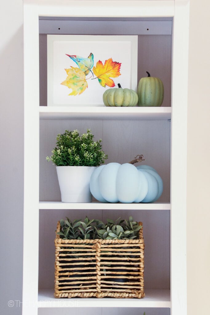symmetrical bookshelf with leaf art and woven wire basket