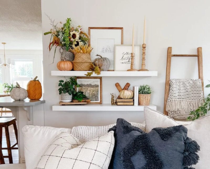 Open shelving behind sofa styled with fall decor - foliage, pumpkins, art sign