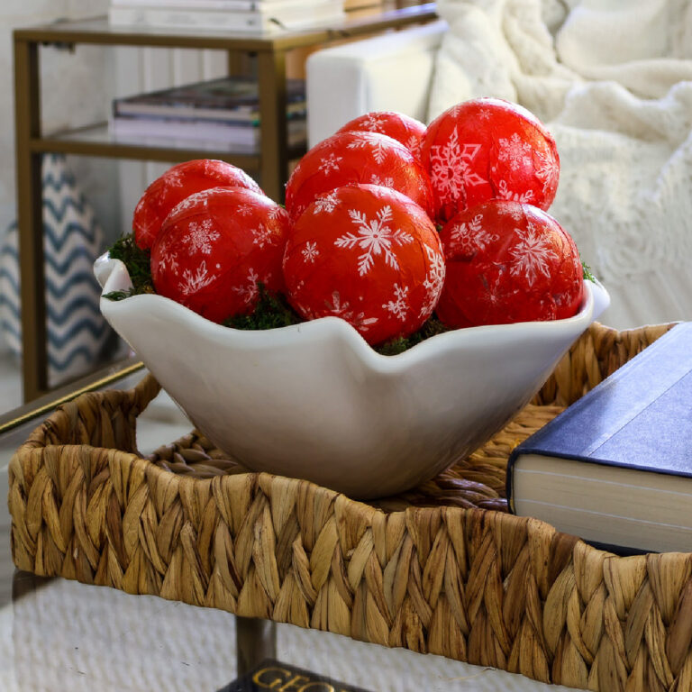 white bowl of red and white ornaments on coffee table in woven tray