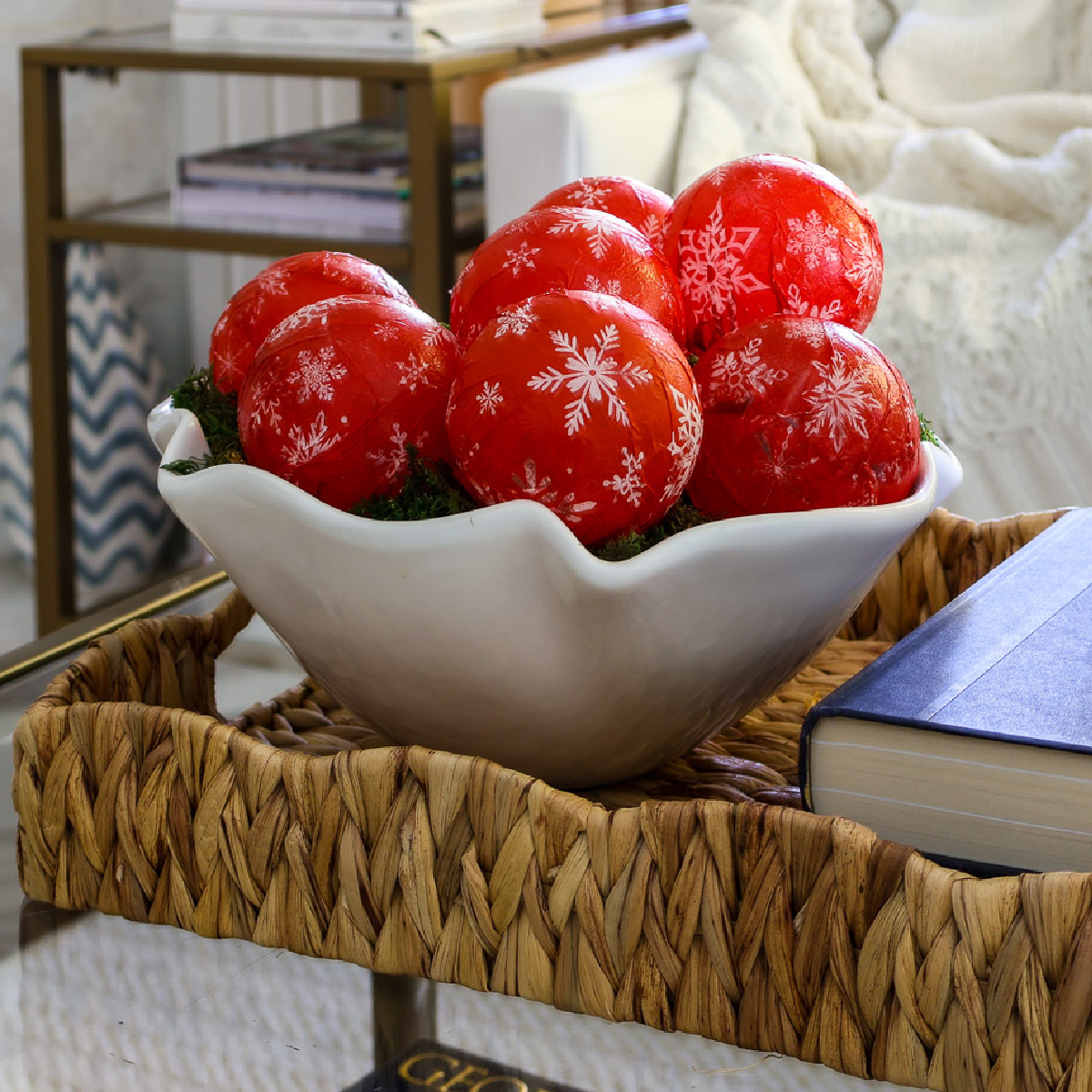 white bowl of red and white ornaments on coffee table in woven tray