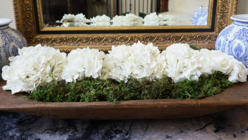 6 all white flowers in doughbowl on entry chest with mirror in background