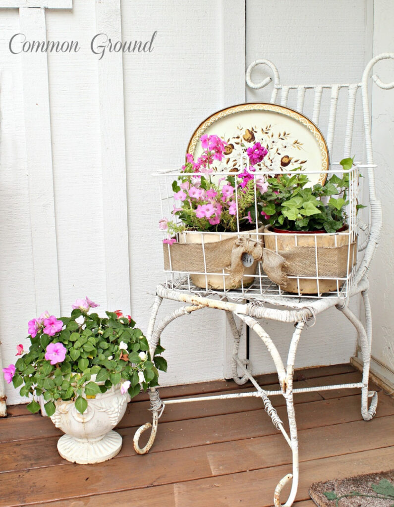 white vintage chair with planter of flowers and flowers in white planter on ground