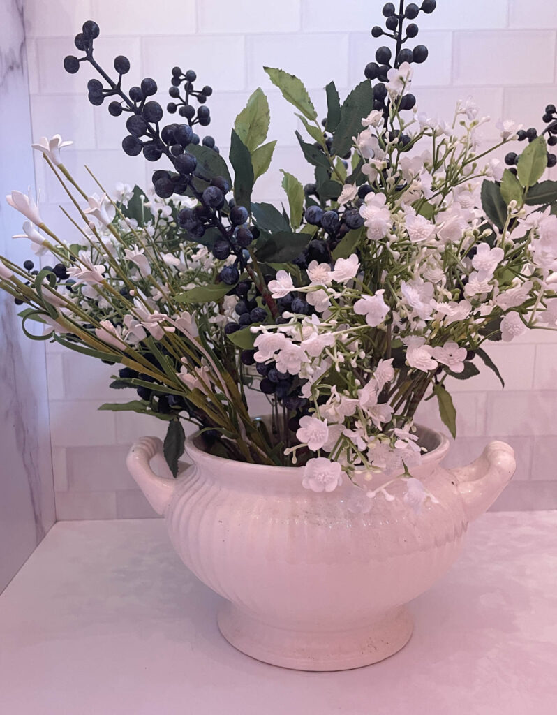 faux white flowers and blueberry stems in white soup tureen