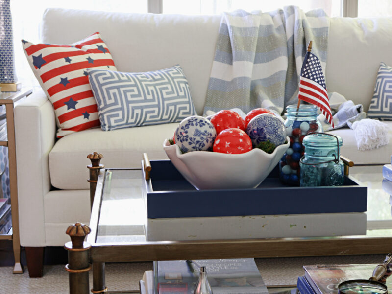 white bowl of red and blue balls in blue tray on coffee table and pillow on sofa