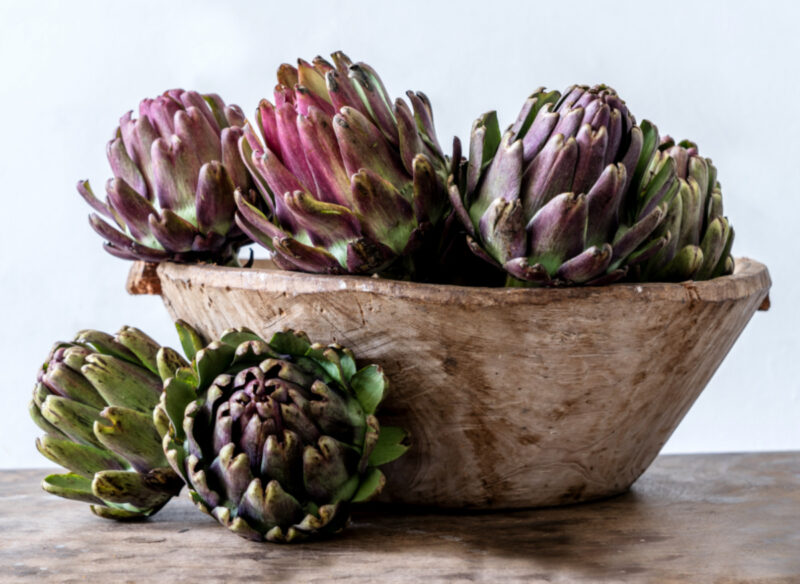 purple artichokes in wood bowl