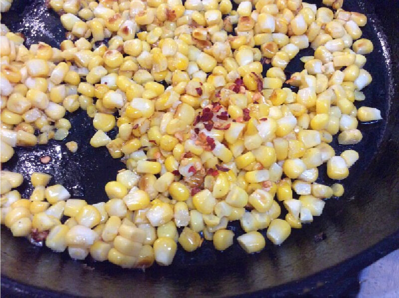 sauteing corn and red chili flakes in cast iron skillet