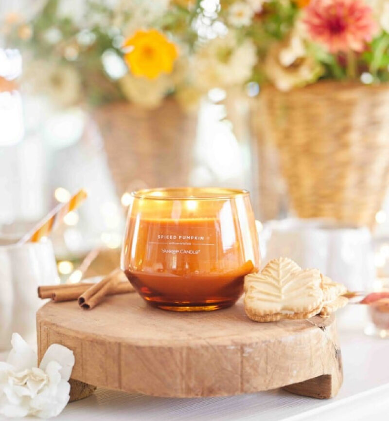 fall candle in arrangement with flowers in the background