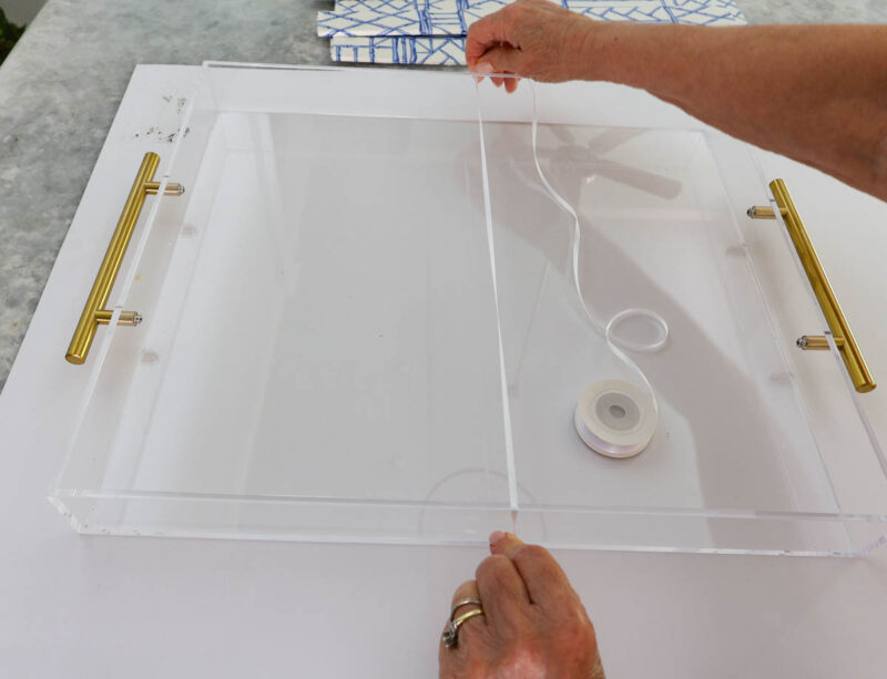 clear acrylic tray with brass handles on foam board