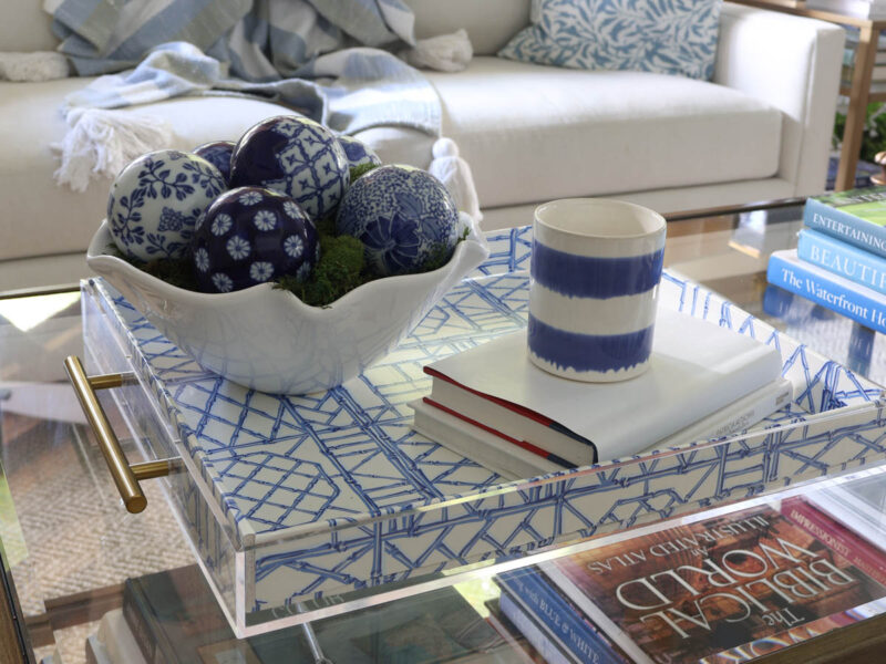 white bowl of blue ceramic balls on blue acrylic tray with white and blue stripe container