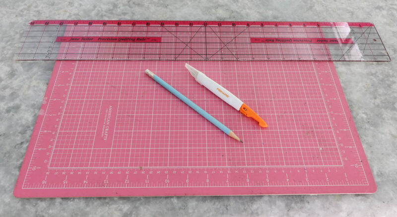 cutting mat, craft knife, pencil, clear quilting ruler