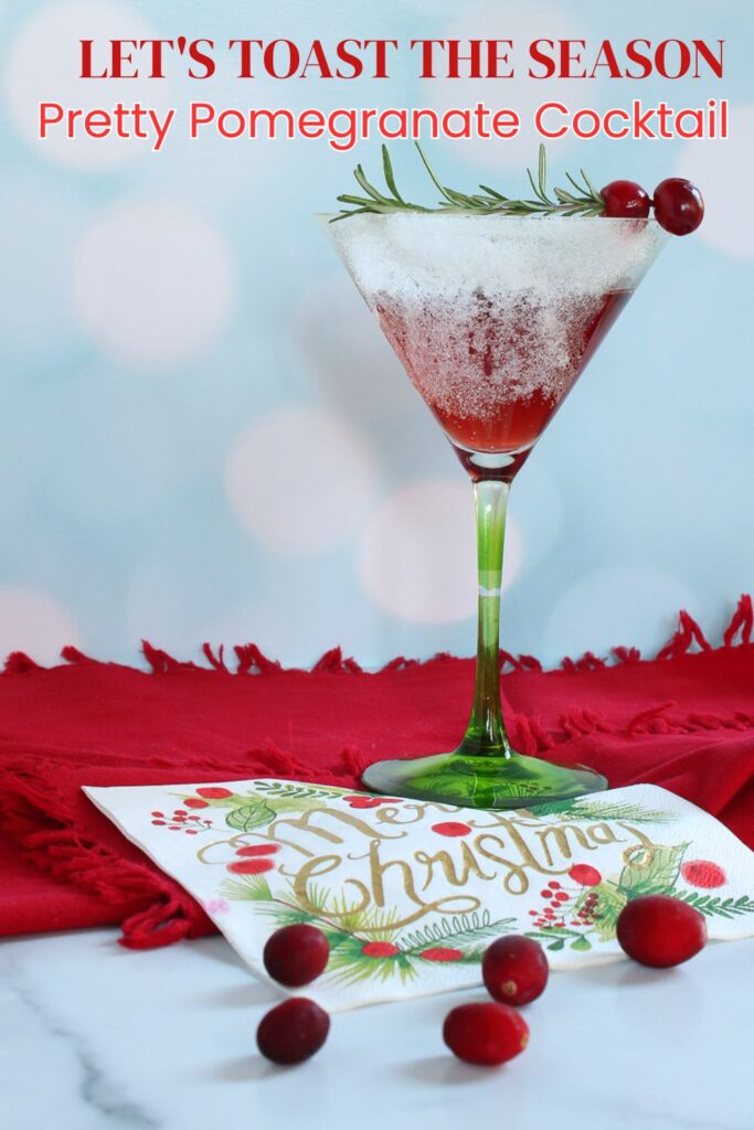 pomegranate cocktail displayed  on a napkin with a Christmas napkin and cranberries