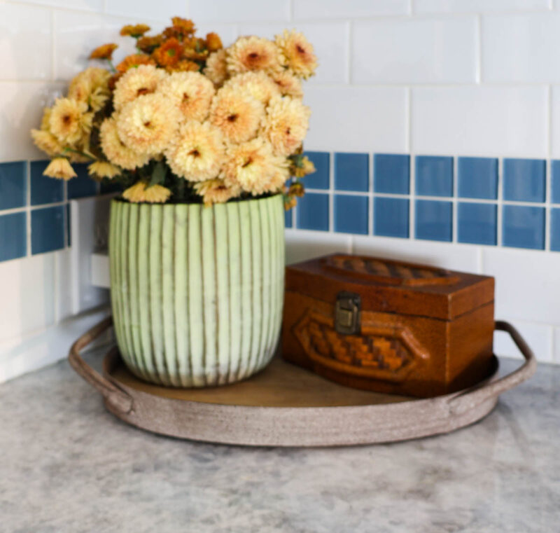 pale green planter of fresh flowers with a brown vintage box on wood and metal tray