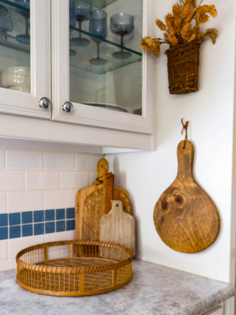 fall corner vignette with woven basket tray, wood cutting boards, and hanging basket with flowers