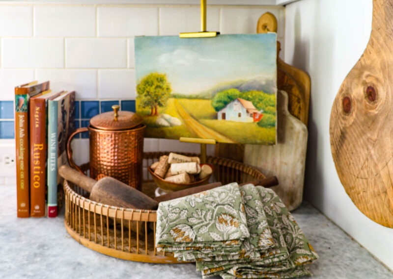 fall decor vignette with copper pitcher, napkins, bowl of wine corks with three cookbooks