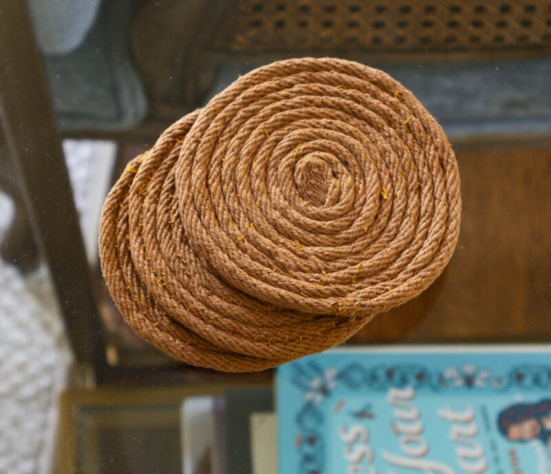 three braided rope coasters in brown on glass table