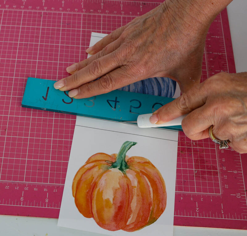 cutting out watercolor pumpkins with ruler and X-acto knife