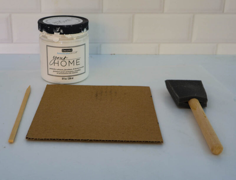 jar of white paint with square piece of cardboard