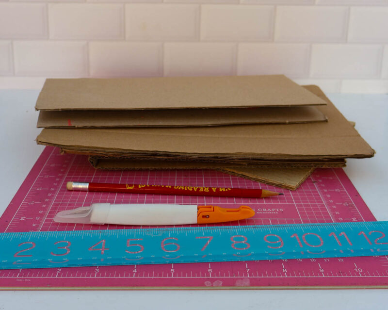stack of cardboard with ruler, pencil, and x-acto knife