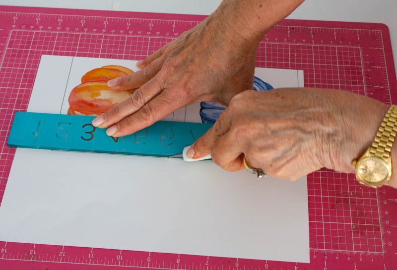 cutting out watercolor pumpkins with ruler and X-acto knife