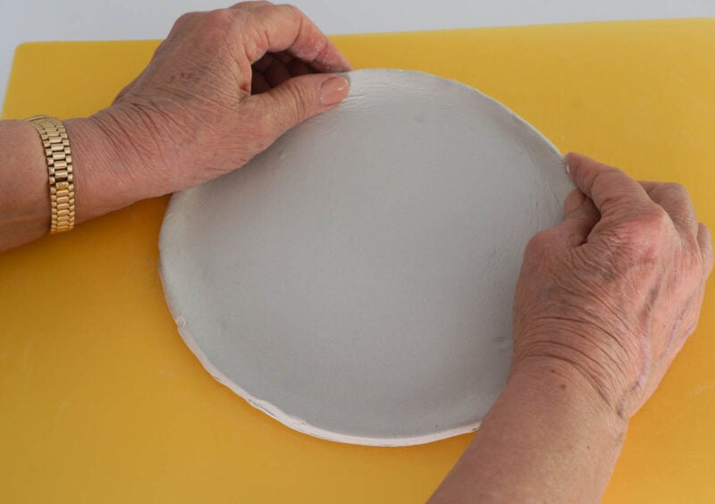 making a raised rim around the clay circle with fingers