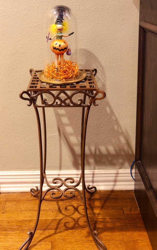 small witch in cloche on metallic tray on metal table