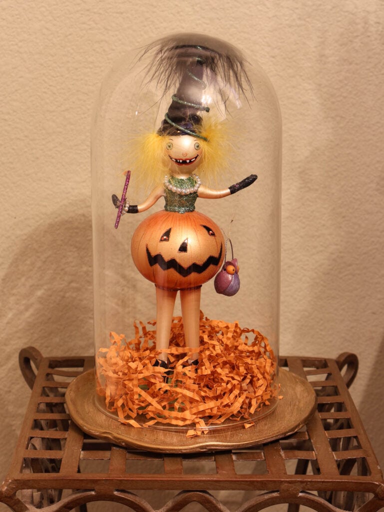 small witch in cloche on metallic tray on metal table